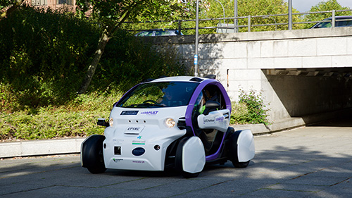 Robotic Pod driving out of underpass into shadow.