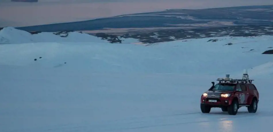 Red vehicle on glacier at sunset in Iceland. 