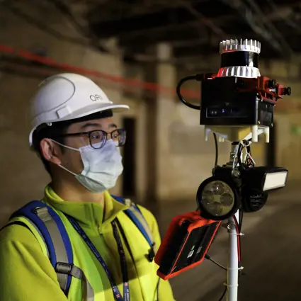 Student holding hand held lidar in underground site.