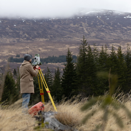 Man looking through Leica Laser Tracker with Scottish mountains in background. 