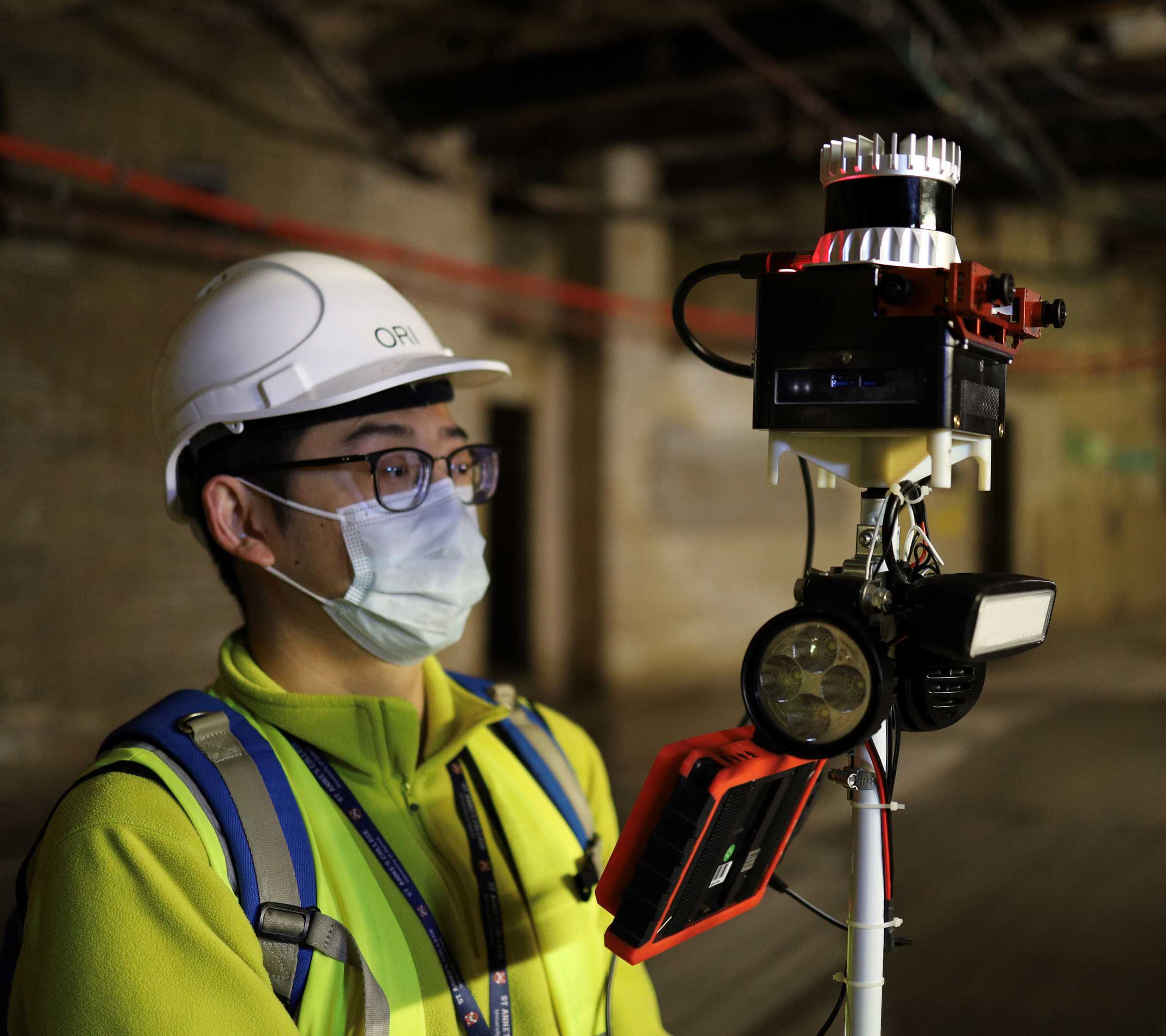 Student holding hand held lidar in underground site.