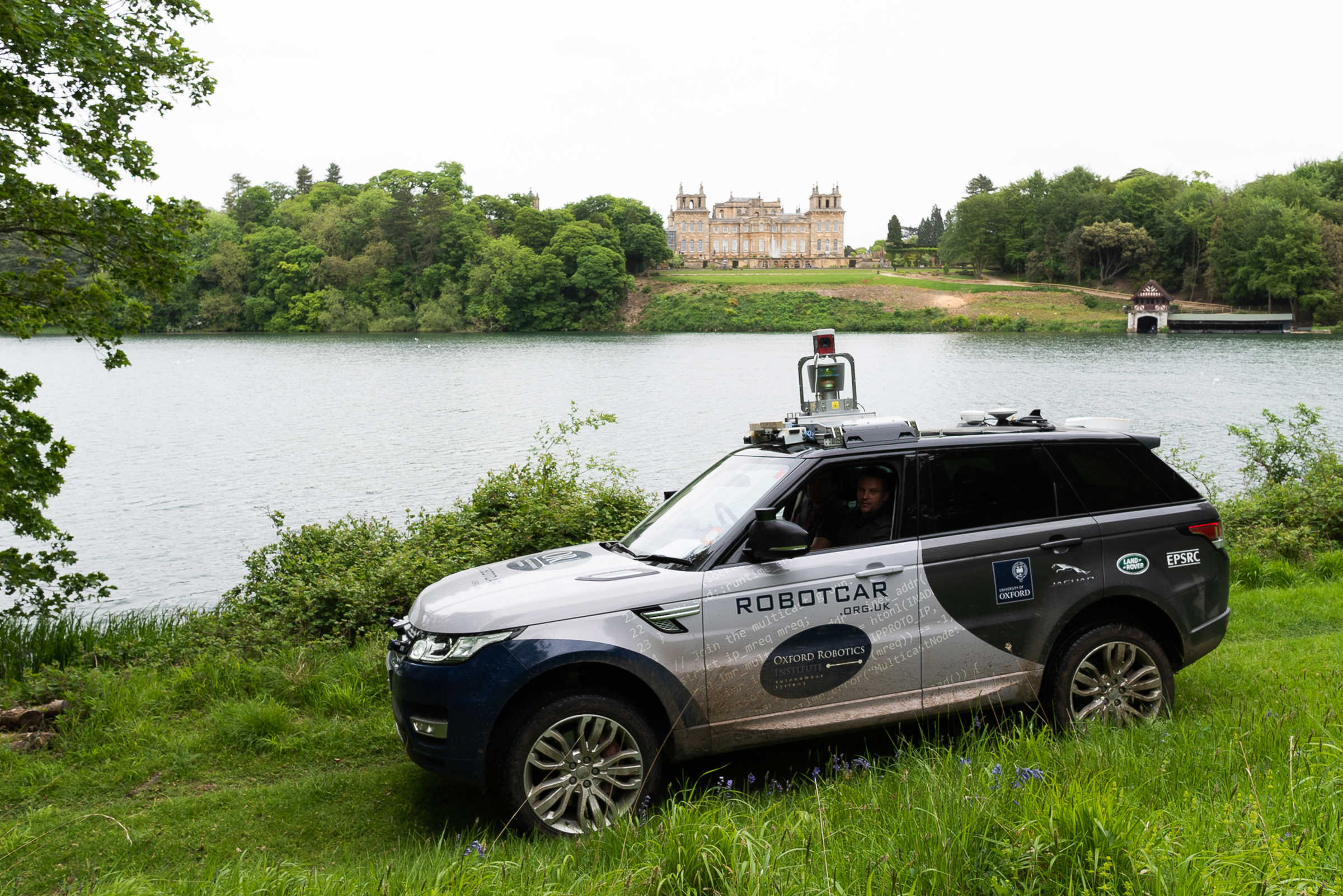 JLR Range rover parked on green grass in front of river. 