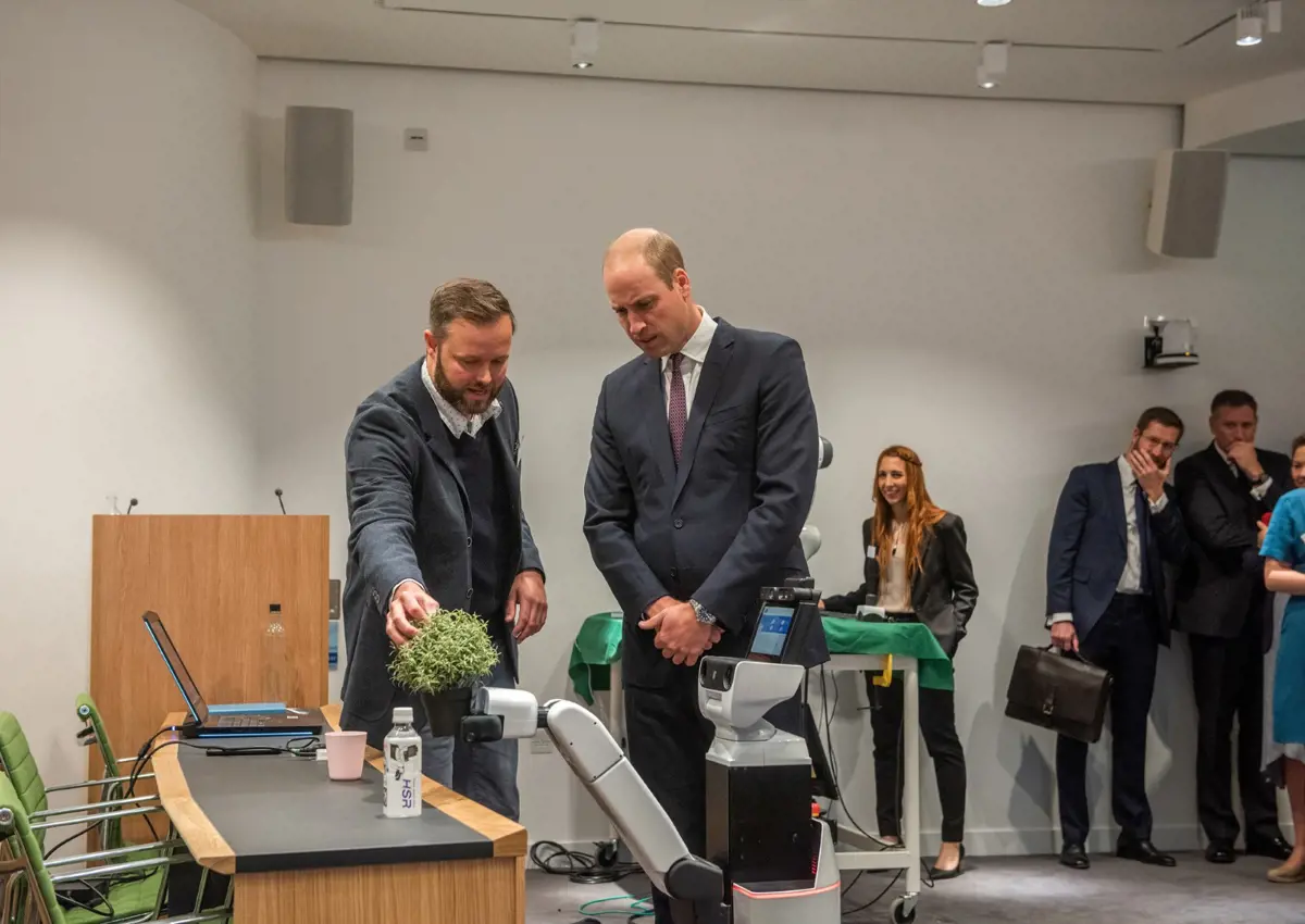 Duke Of Cambridge and Lars Kunze looking at the HSR Robot at Keble College. 
